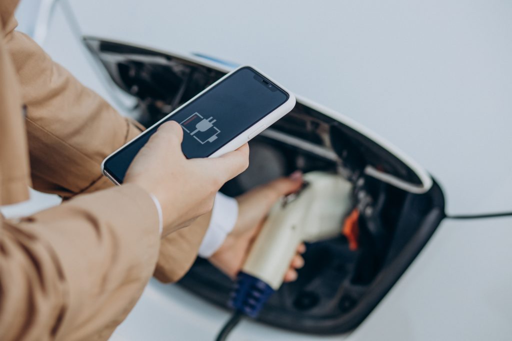 woman holding charger charging electric car close up